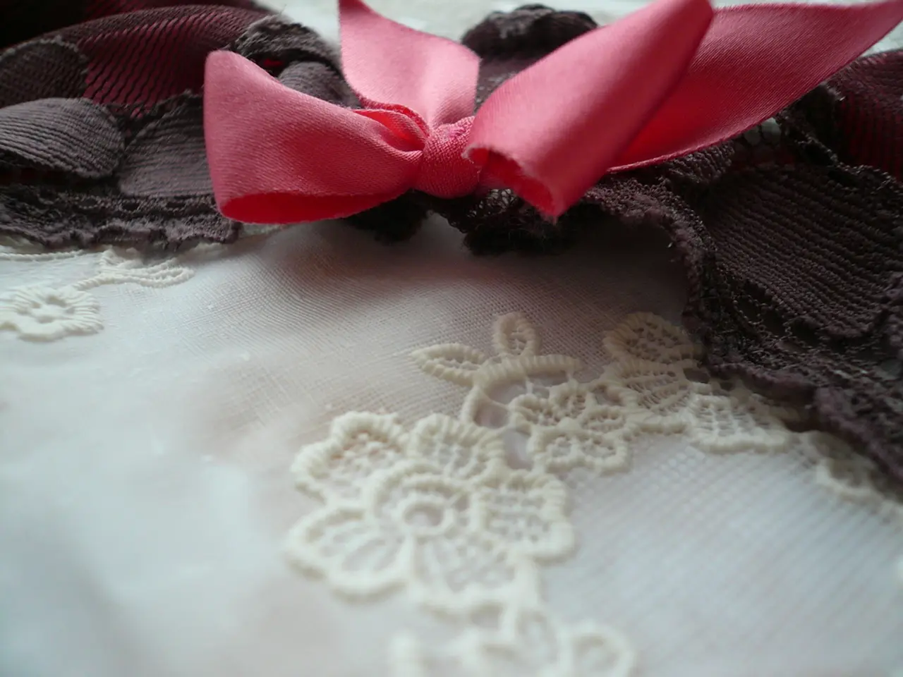 In this picture there is a floral design on the white fabric. There is a pink knitted fabric and at...