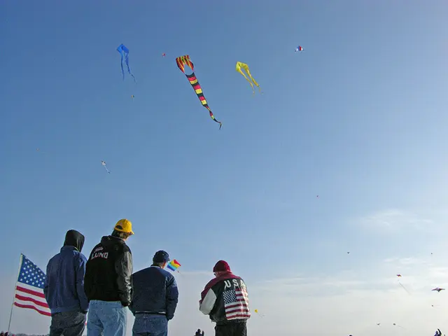 In the foreground I can see four persons are standing and flying kites in the air. The background...